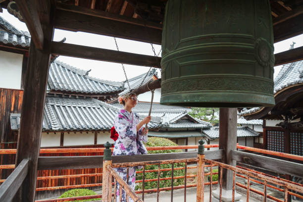 若い美しい女性はempleで鐘を鳴らす - 神社 ストックフォトと画像